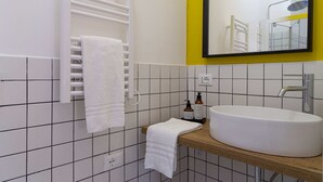 Ein Badezimmer mit einem weißen Waschbecken, einem Spiegel und einem Handtuchhalter.