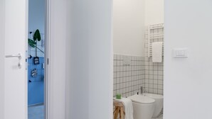 Ett badrum med en vit toalett, bidé och ett litet bord med en handduk.