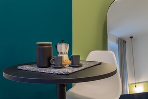 Uma mesa com uma cafeteira, duas xícaras e um pote sobre um descanso de palha.
