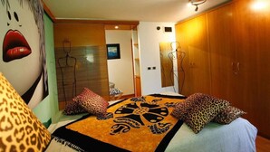 A bedroom with a bed, leopard print pillows, a patterned rug, and a wall with a large painting. - Casa Vacanza Diana (roma)