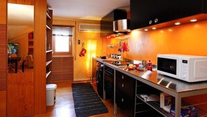 A compact kitchen with a microwave, stove, and wooden cabinets. - Casa Vacanza Diana (roma)