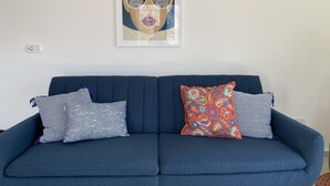 En blå soffa med mönstrade kuddar och ett inramat konstverk ovanför.