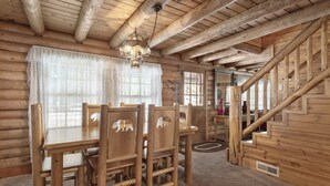Een houten interieur met een eettafel, stoelen, een kroonluchter en een trap.