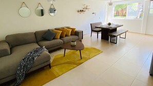 A modern living room with a sofa, coffee table, and dining table.