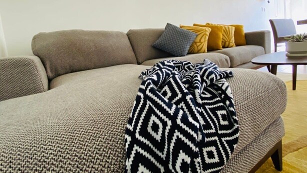 A living room with a sofa, throw pillows, a blanket, and wall-mounted mirrors.