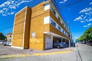 A multi-story building with a yellow facade, a covered parking area, and a clear blue sky.