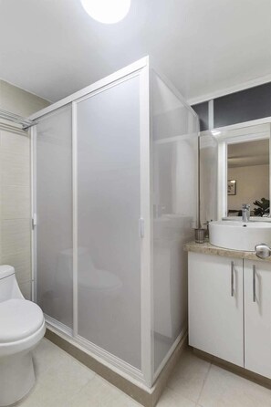 A bathroom with a shower enclosure, toilet, and sink area.
