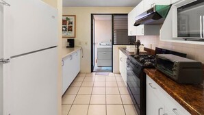 Una cocina compacta equipada con refrigerador, estufa, microondas y tostadora.