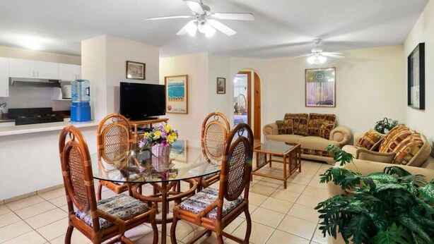 Una sala de estar con sofá, una mesa de comedor con sillas, televisor y ventiladores de techo.