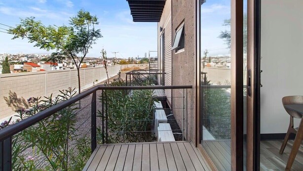 Un balcon avec vue sur la ville, une terrasse en bois et une porte vitrée donnant sur une pièce.