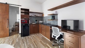 Une cuisine compacte avec des meubles en bois, un four à micro-ondes, un grille-pain et un téléviseur.