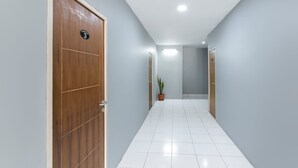 A hallway with a wooden door marked "3", a potted plant, and a tiled floor. - Oyo 3130 Valley (Lembang)
