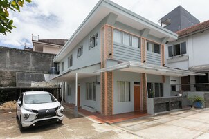 A modern two-story house with a covered porch, a car parked in front, and a small garden area.