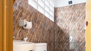 A bathroom with a toilet, sink, and marble walls. - Oyo 3130 Valley (Lembang)
