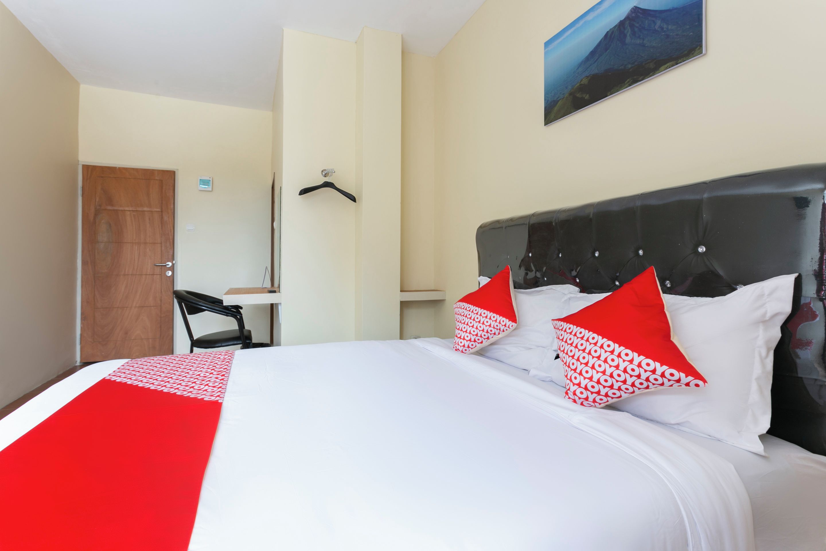 A hotel room with a bed, a desk, a chair, and a door.