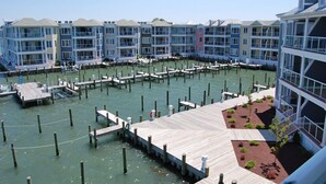 A waterfront hotel with multiple balconies, a dock area, and a landscaped garden. - Bayside & Beyond- 1st Floor Waterfront Condo with Pool, Gym & Boat Slip (Chincoteague)