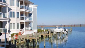 A waterfront property with a multi-story building, docked boats, and a clear view of the water. - Bayside & Beyond- 1st Floor Waterfront Condo with Pool, Gym & Boat Slip (Chincoteague)