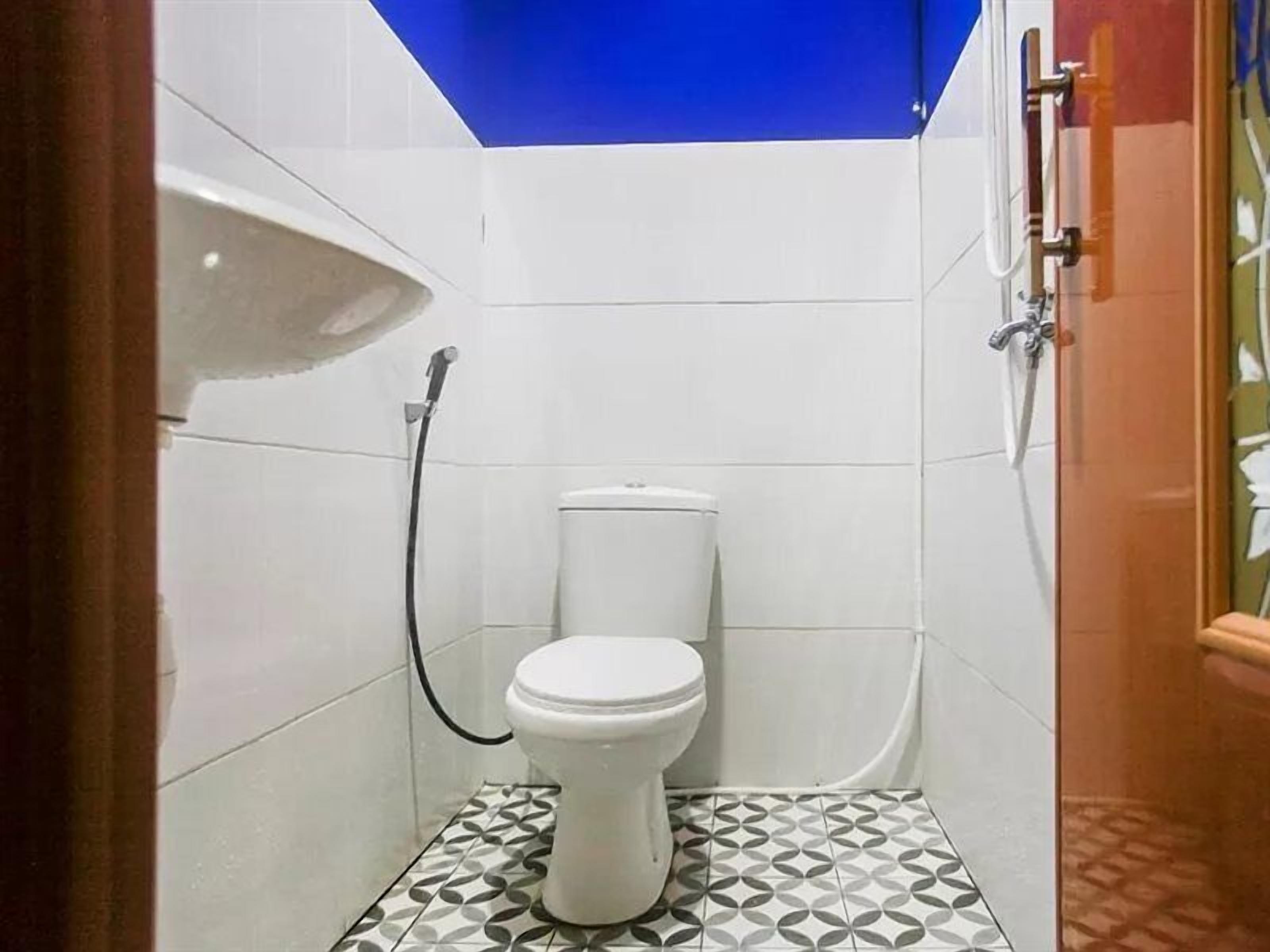 A small, compact bathroom with a toilet, a shower, and a sink.