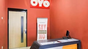 A reception area with a red wall, a wooden door, and a reception desk with a 'SAY NO' poster. - OYO 3456 Citara Jaya Guesthouse (Bekasi)
