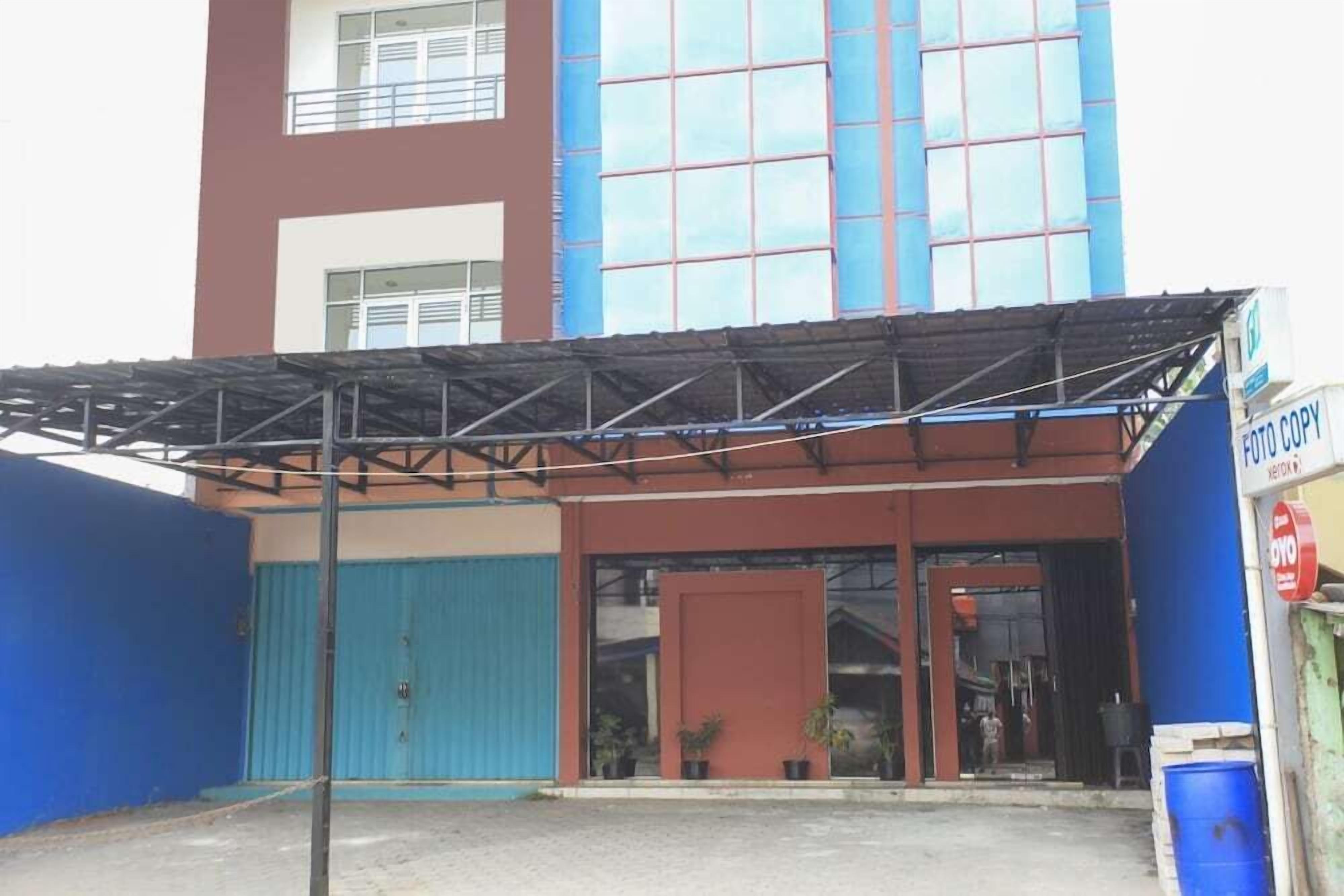 A building with a covered entrance, a blue garage door, and a sign for a photo copy service.