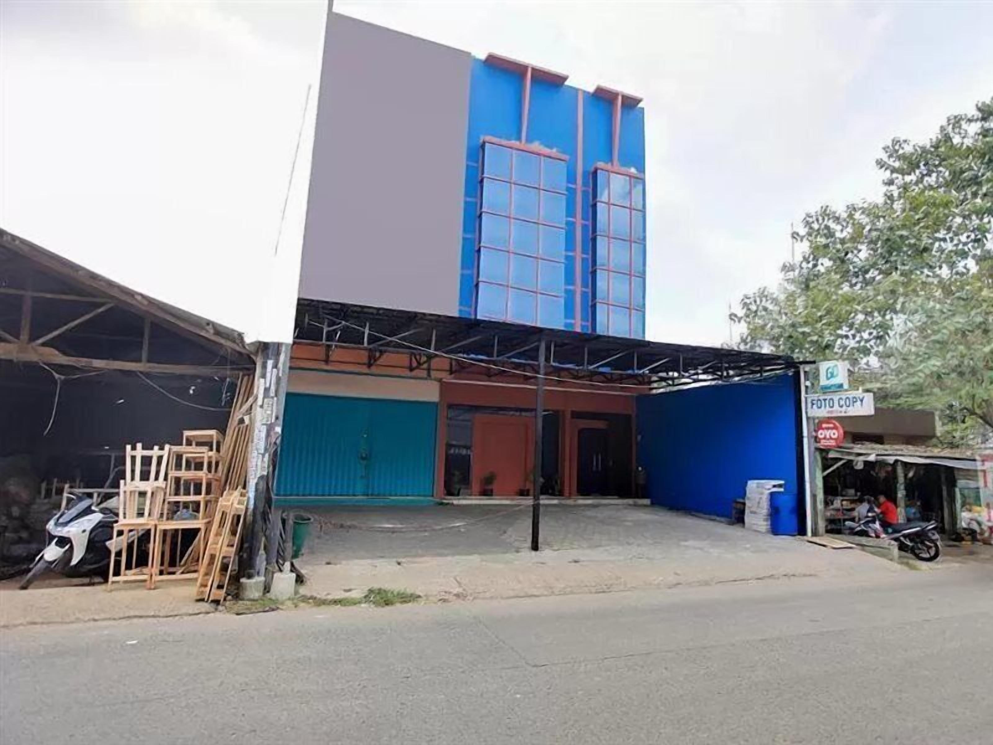 Un bâtiment à la façade bleue et grise, doté d’une entrée couverte et d’une enseigne indiquant « Foto Copy ».