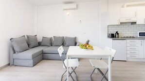 Una cocina moderna con armarios blancos, encimera blanca y comedor con mesa y sillas blancas.