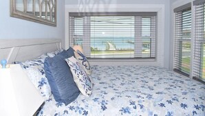 Ein Schlafzimmer mit Bett, Nachttisch, einem Fenster mit Jalousien und Meerblick.