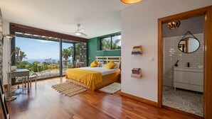 Ein Schlafzimmer mit Bett, Schreibtisch und Meerblick.