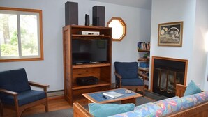 A living room with a wooden entertainment unit, a sofa, two chairs, a coffee table, and a fireplace.