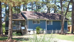 A single-story house with a front porch, a covered deck, and a small front yard.