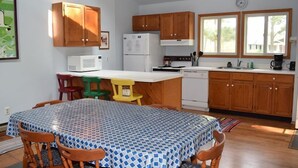 A compact kitchen with wooden cabinets, a white refrigerator, a microwave, and a coffee maker.