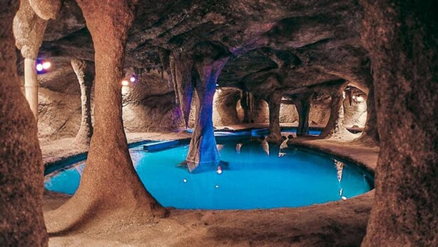 Ein unterirdischer Pool mit natürlichen Felsformationen und einer zentralen Säule.