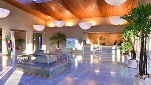 Eine großzügige Lobby mit Empfangsbereich, Sitzgelegenheiten und tropischer Bepflanzung.