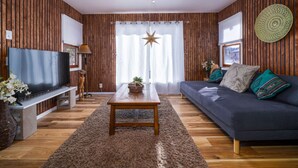 Un salón con paneles de madera, televisor, sofá y mesa de centro.