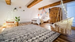 Un dormitorio acogedor con cama, sillón colgante y alfombra estampada.