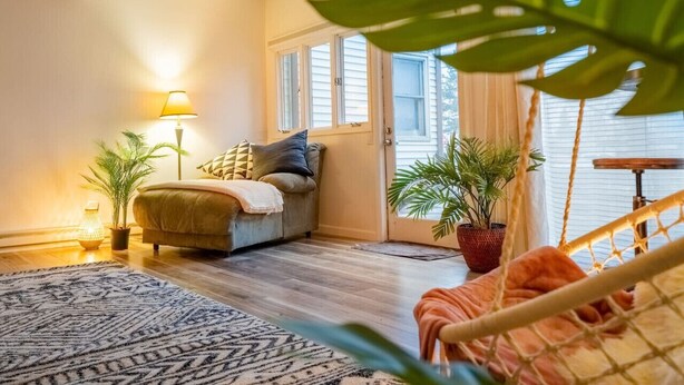 Una sala de estar acogedora con un sofá, una hamaca y plantas en macetas.