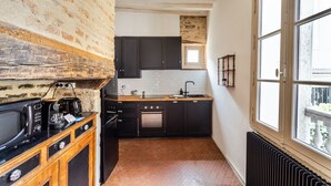 A kitchen with dark cabinets, a tiled backsplash, and a window with a view. - Dame de Coeur - Appartement spacieux en plein centre historique (Rennes)