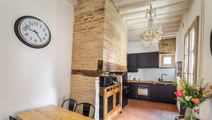 A kitchen with a brick wall, wooden cabinets, and a dining area with a wooden table and chairs. - Dame de Coeur - Appartement spacieux en plein centre historique (Rennes)