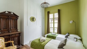 A room with two beds, a wooden cabinet, a chair, and a hanging light fixture. - Dame de Coeur - Appartement spacieux en plein centre historique (Rennes)