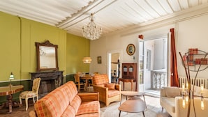 A cozy living room with a fireplace, a dining area, and a balcony with curtains. - Dame de Coeur - Appartement spacieux en plein centre historique (Rennes)