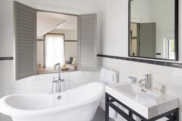 A modern bathroom with a freestanding bathtub, a vanity with a mirror, and a towel rack. - The Chequit (Shelter Island Heights)