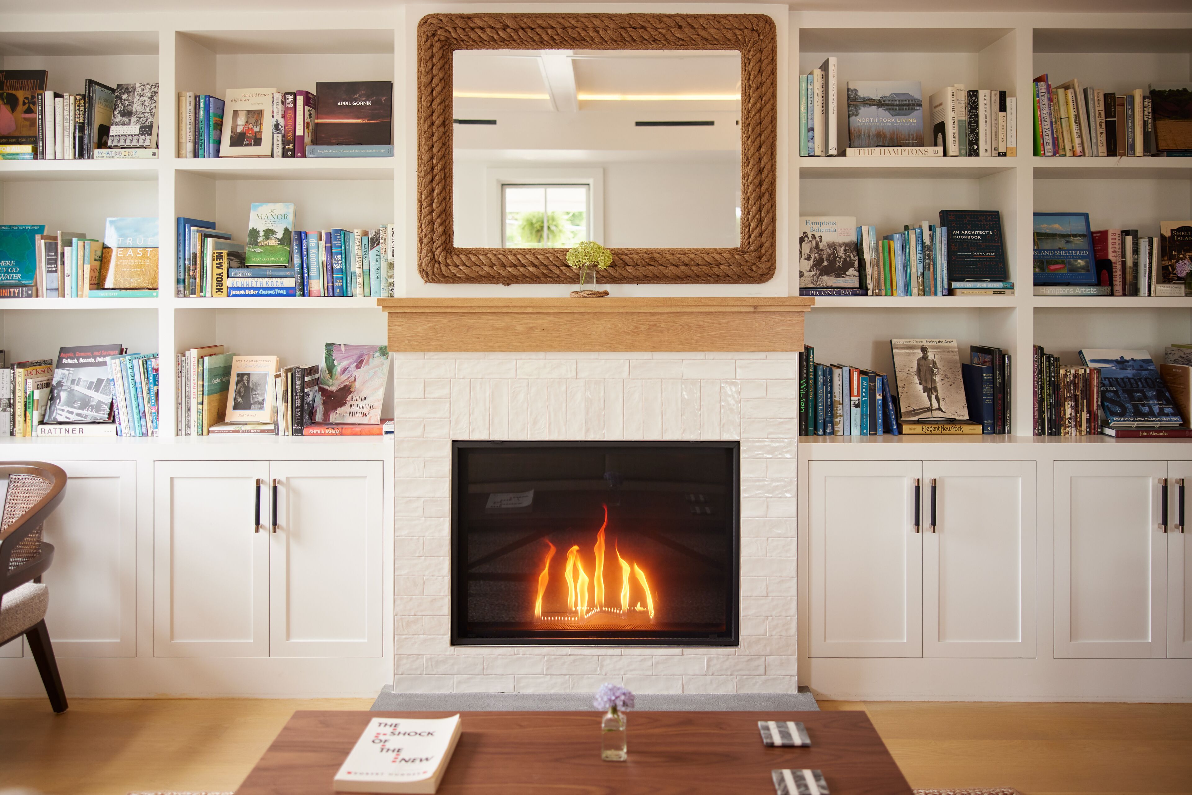 A living room with a fireplace, bookshelves, and a mirror.