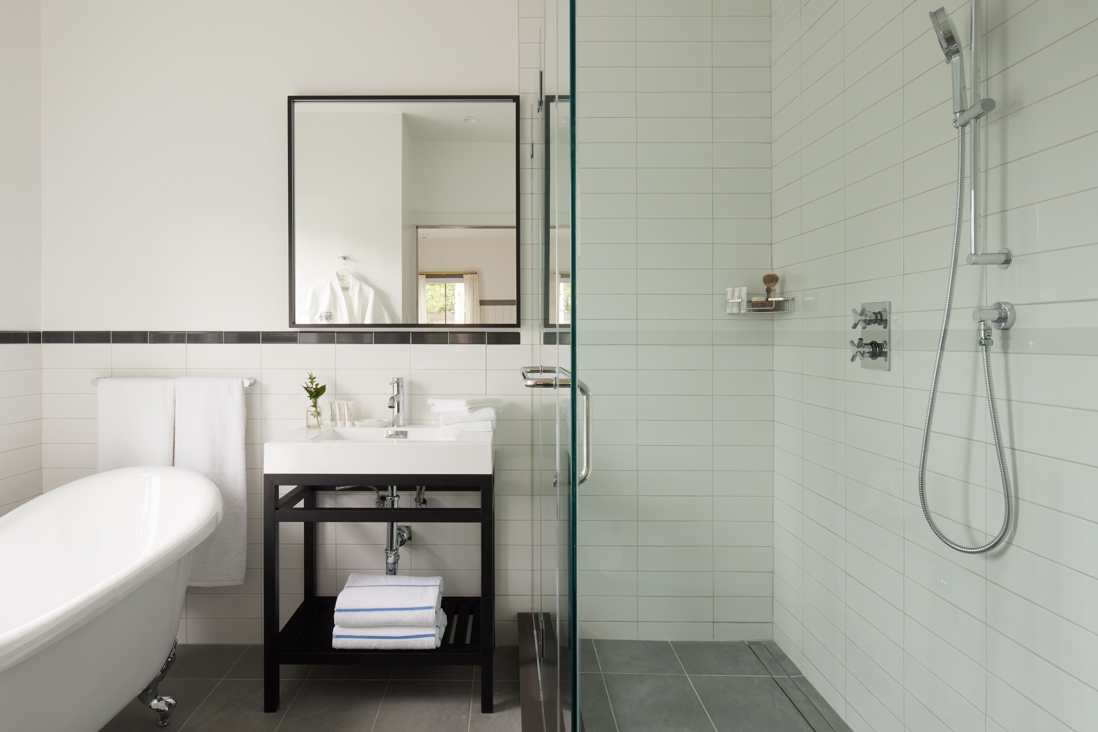 Une salle de bain moderne avec une baignoire sur pieds, une douche à parois de verre et un meuble-lavabo avec un miroir.