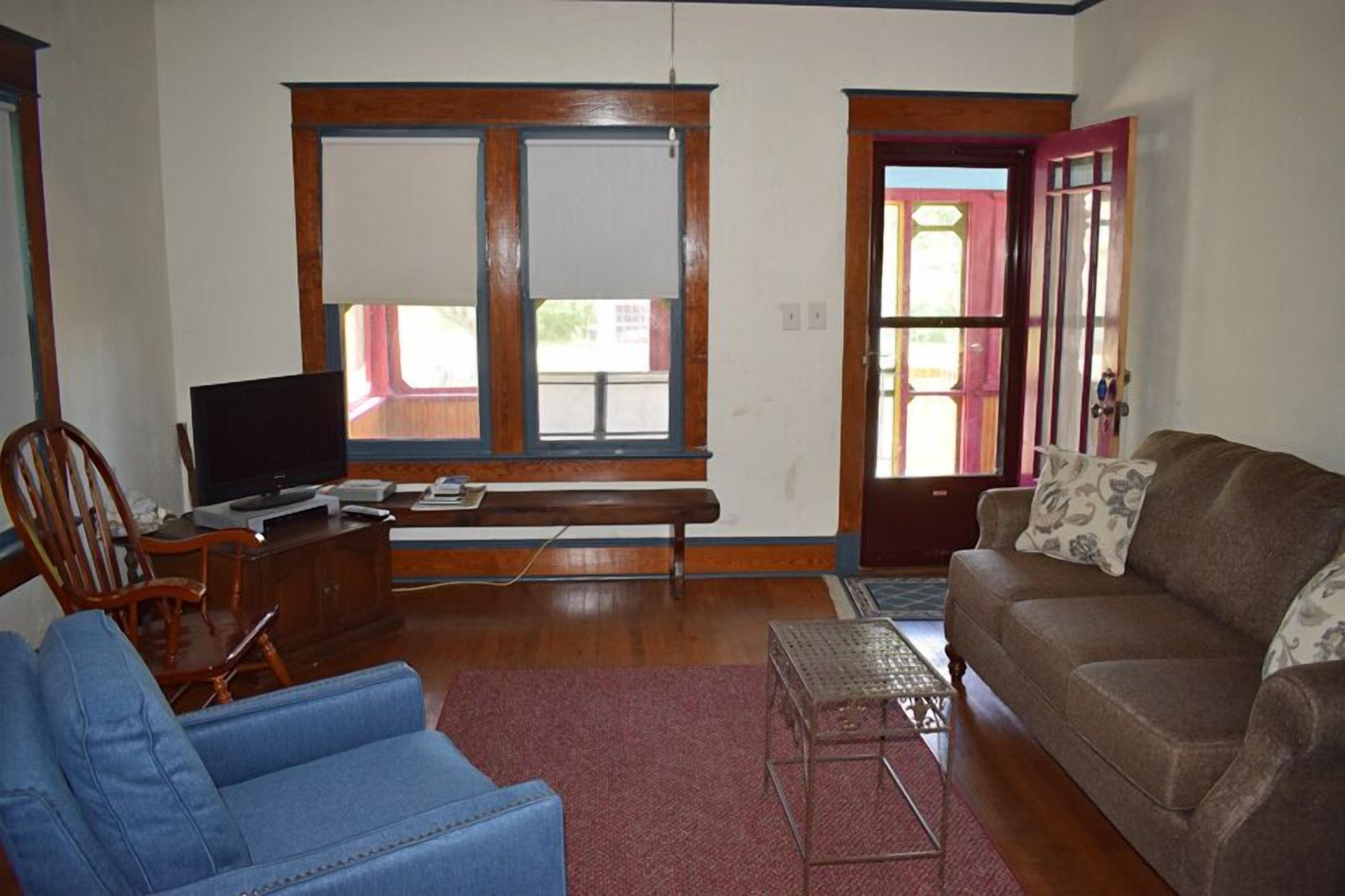 A living room with a blue armchair, a brown sofa, a television, and a wooden bench.