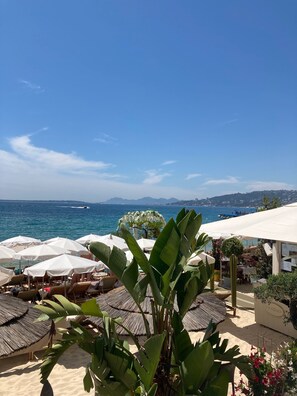 A beachside resort with sun loungers, umbrellas, and a view of the sea.