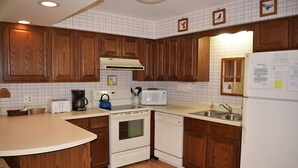 Una cocina con armarios de madera, estufa blanca, microondas y refrigerador.