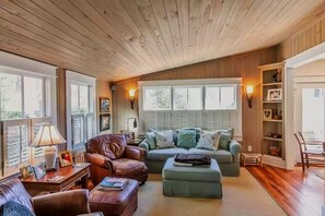 Relax in a warm and inviting living space with a comfortable seating area, wooden table, and bookshelf.