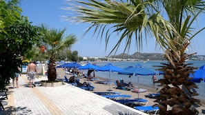 Enjoy a serene beachside retreat with stunning sea views, shaded by palm trees and comfortable lounge chairs.