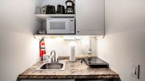 Une cuisine compacte équipée d’un four à micro-ondes, d’une machine à café et d’un évier.