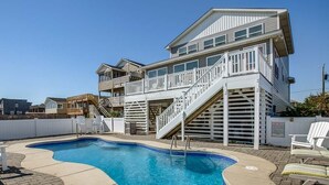 Ein zweistöckiges Haus mit Swimmingpool, einer Terrasse und einer Treppe, die zu der oberen Etage führt.